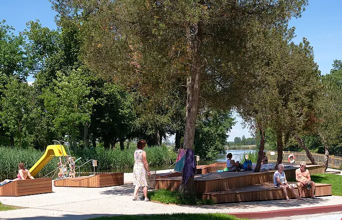Blick auf Sitzgelegenheiten im Flussfreibad. Links im Hintergrund sieht man eine Rutsche.