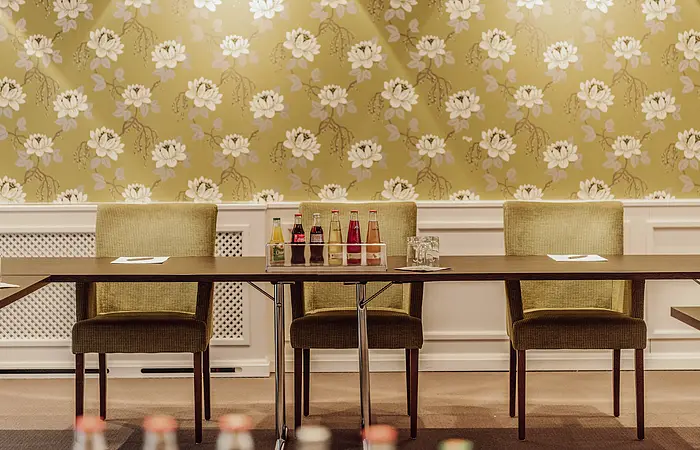 Drei Stühle mit einem Tisch und Getränke im Hotel Eisvogel