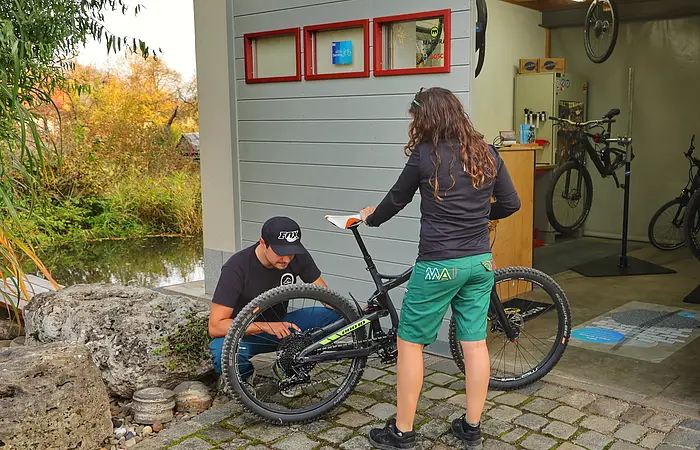 Auf dem Bild sieht man einen der beiden Inhaber der S2 Radlwerkstatt, der gerade ein Fahrrad von einer Kundin repariert.