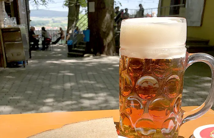 Drei Bratwürste mit Kraut und Brot auf einer Bierbank, dazu eine Maß Wettelsheimer Keller Märzen