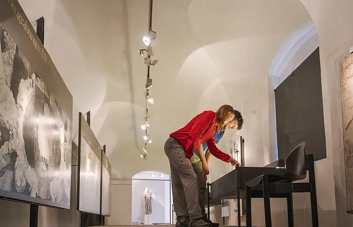 In den Ausstellungsräumen beugen sich zwei Besucher über eine Ausstellungsvitrine.