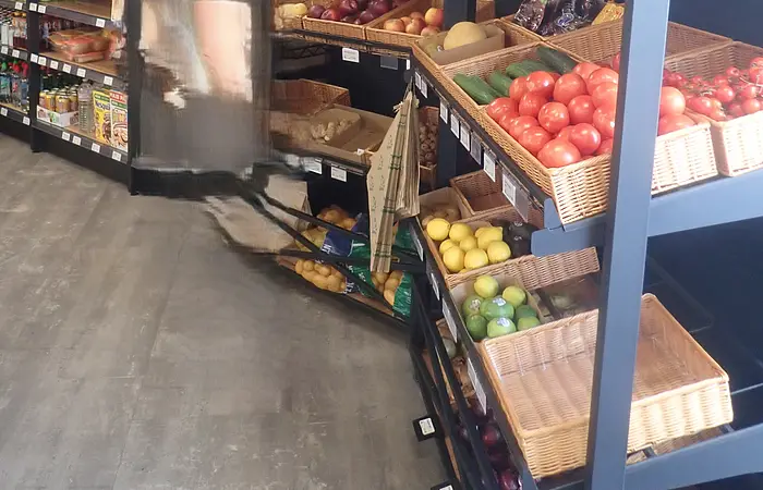 Regal mit frischem Obst und Gemüse in einem Lebensmittelgeschäft mit Holzbalkendecke.